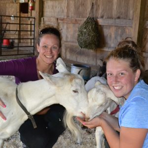 two smiling women with two white goats at east hill farm