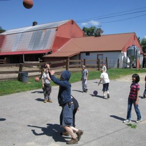 Young farm school kids playing basketball on a clear sky day at East Hill Farm