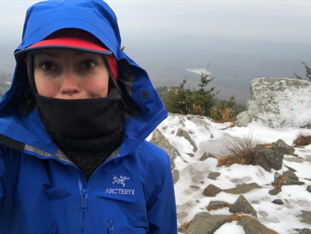 woman at the summit of mt monadnock bundled up in winter clothing from east hill farm