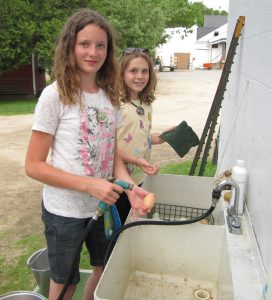 two smiling girls cleaning eggs at east hill farm school